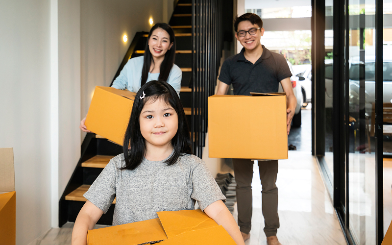 Family carrying moving boxes when moving to a smaller house.