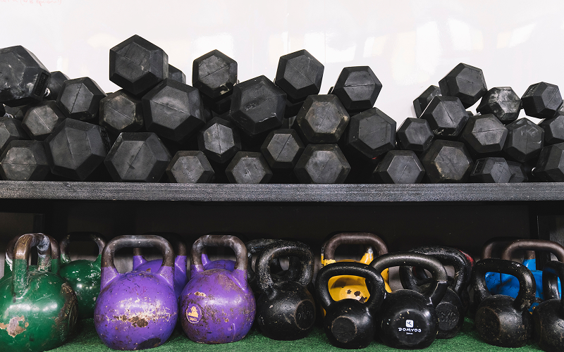 Dumbbells and kettlebells stacked on racks for gym equipment moving